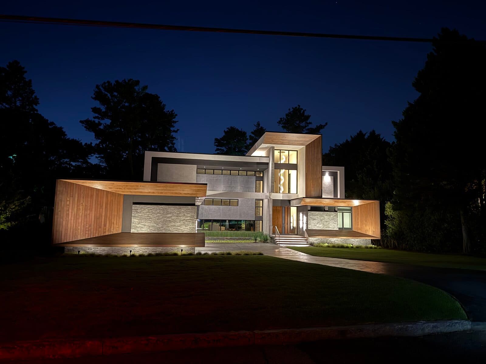A modern home at dusk with warm interior lighting, run as one system