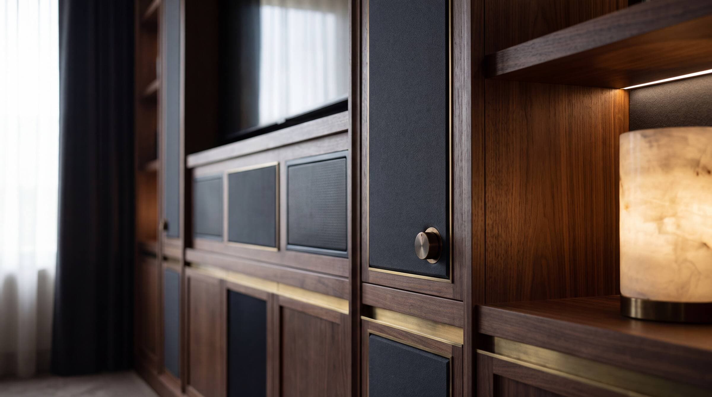 Discreet high-end equipment integrated into walnut cabinetry with brass accents