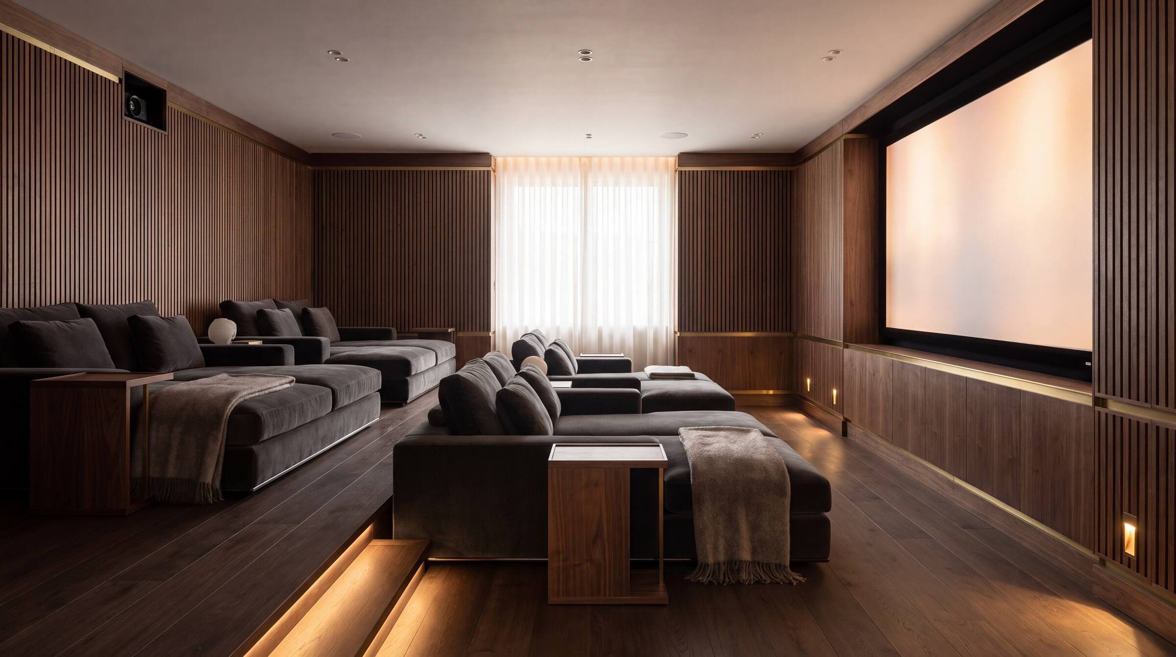 Private home cinema with tiered seating and a glowing screen